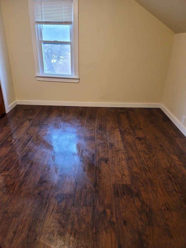 additional living space featuring baseboards, lofted ceiling, and dark wood-type flooring