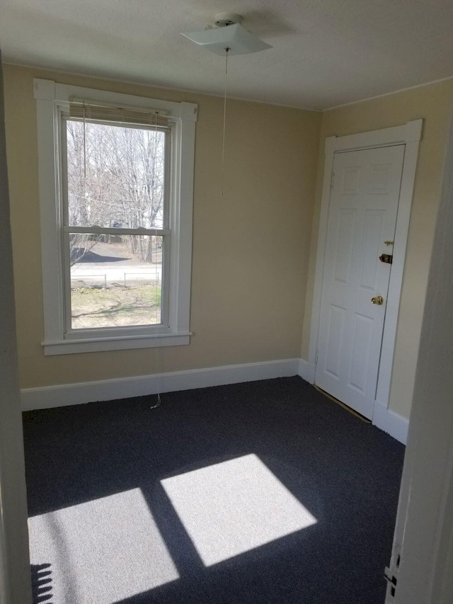 carpeted spare room with a ceiling fan and baseboards