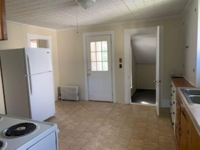 kitchen with crown molding, white appliances, radiator heating unit, a ceiling fan, and light floors