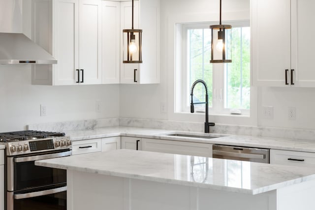 kitchen with pendant lighting, white cabinets, sink, wall chimney exhaust hood, and stainless steel appliances