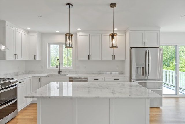 kitchen featuring light hardwood / wood-style floors, sink, white cabinetry, stainless steel appliances, and decorative light fixtures