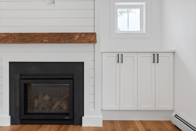 interior details with a baseboard heating unit and hardwood / wood-style flooring