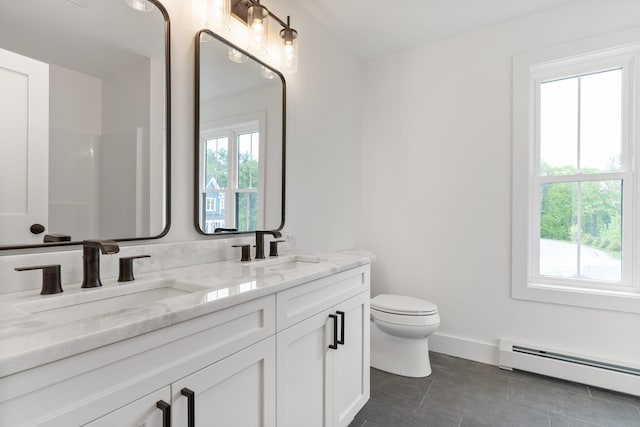 bathroom with vanity, toilet, a baseboard heating unit, and a wealth of natural light