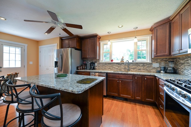 832 College St, Lewiston, ME 04240 - kitchen with stainless steel appliances, a sink, light wood-style floors, a breakfast bar, and recessed lighting