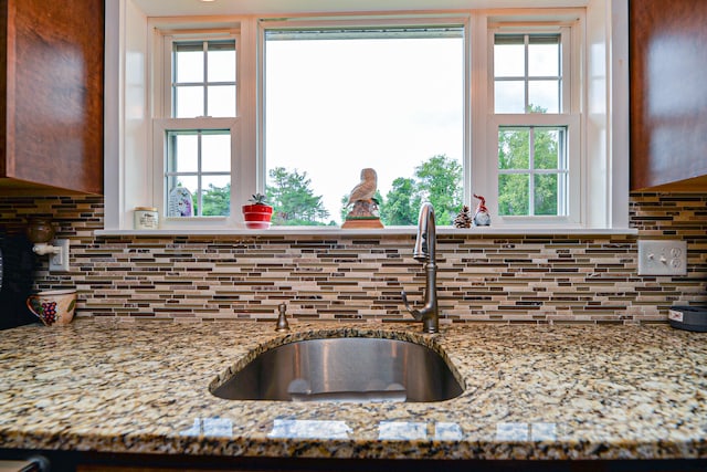 details featuring light stone countertops, decorative backsplash, and sink