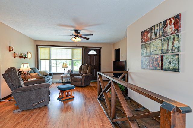 living room with ceiling fan, a textured ceiling, and hardwood / wood-style floors