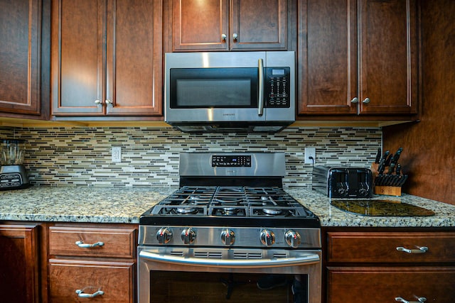 832 College St, Lewiston, ME 04240 - kitchen with stainless steel appliances, backsplash, light stone counters, and dark brown cabinets