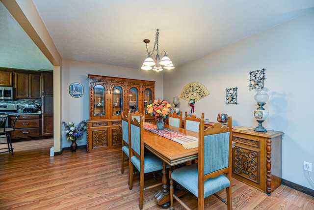 dining room with light hardwood / wood-style floors and a notable chandelier