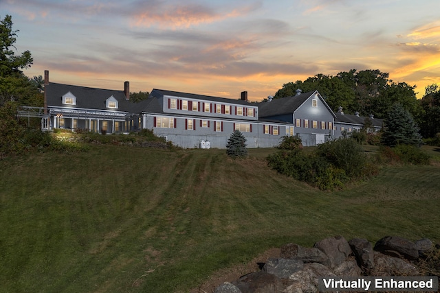 back house at dusk with a lawn