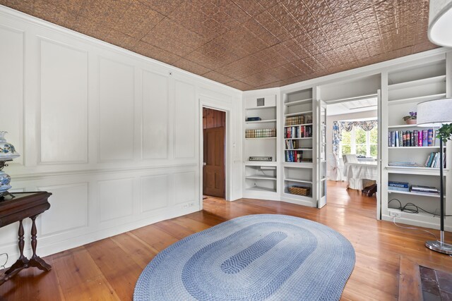 miscellaneous room with wood-type flooring and built in shelves