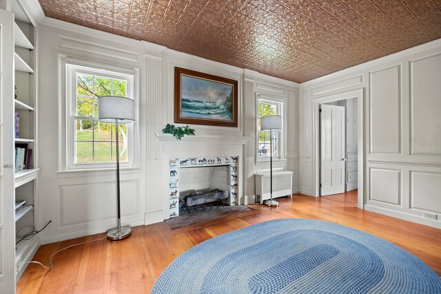 living area with radiator, hardwood / wood-style flooring, built in shelves, and crown molding