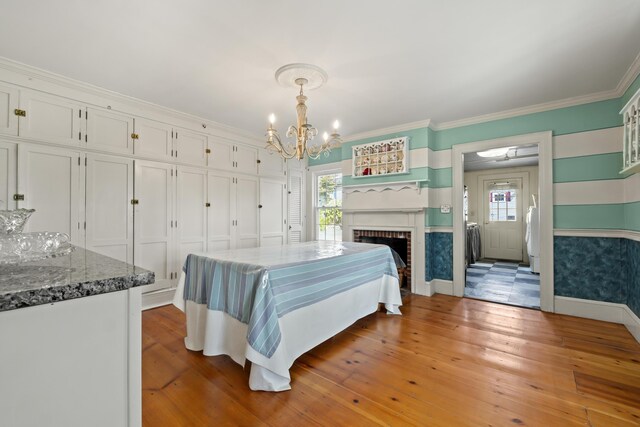 bedroom with light hardwood / wood-style flooring, a brick fireplace, multiple windows, and an inviting chandelier