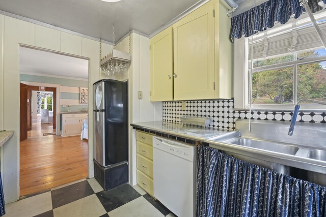 kitchen with ornamental molding, a wealth of natural light, dishwasher, and black refrigerator