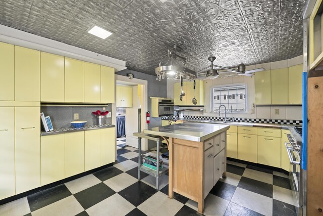 kitchen with decorative backsplash, stainless steel oven, a kitchen island, and sink