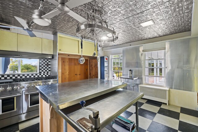 kitchen featuring radiator, ceiling fan, tasteful backsplash, and double oven range