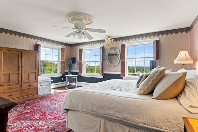 bedroom with a baseboard heating unit, ceiling fan, and a wood stove