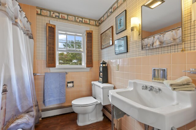 bathroom with tile walls, hardwood / wood-style floors, toilet, and a baseboard heating unit