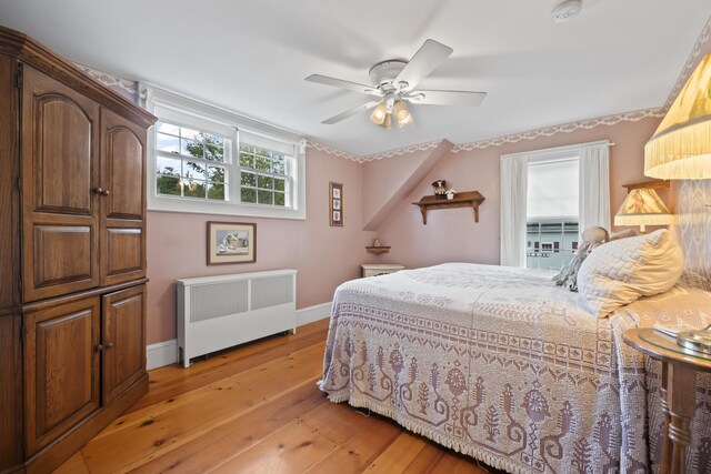 bedroom with ceiling fan, light wood-type flooring, and radiator heating unit