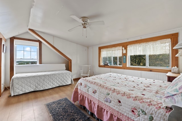 bedroom featuring wood-type flooring, lofted ceiling, multiple windows, and ceiling fan