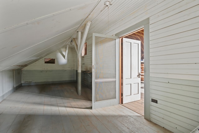 bonus room with wood-type flooring, lofted ceiling, and wood walls