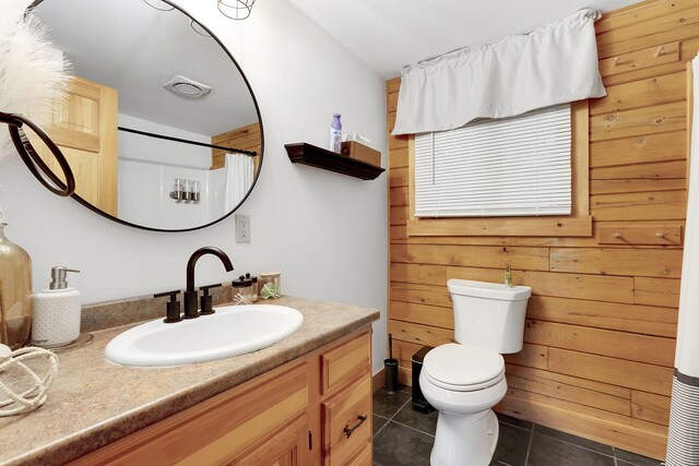 bathroom with vanity, a shower with curtain, wooden walls, tile patterned flooring, and toilet