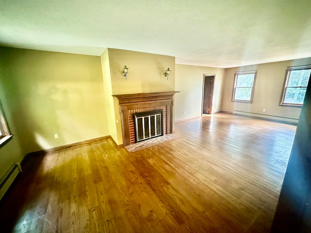 unfurnished living room featuring hardwood / wood-style flooring, a fireplace, and baseboard heating