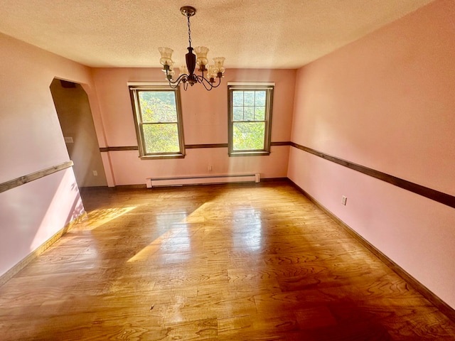 spare room with an inviting chandelier, light wood-type flooring, a textured ceiling, and a baseboard radiator