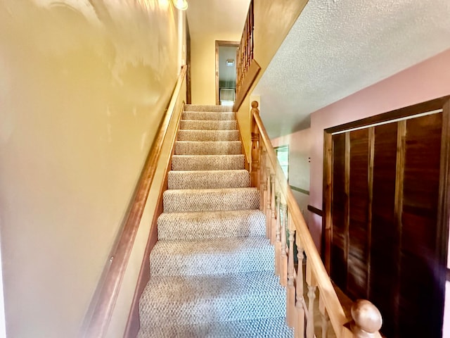 stairway featuring a textured ceiling