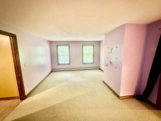 empty room featuring light colored carpet, a baseboard radiator, and a textured ceiling