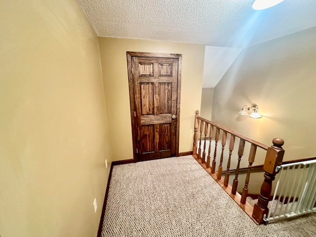 stairway featuring a textured ceiling and carpet