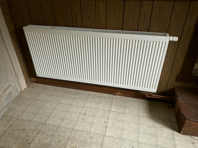 room details featuring wood walls and radiator heating unit