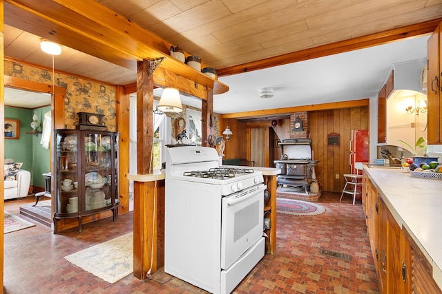 1276 State Route 32, Bristol, ME 04564 - kitchen featuring brick patterned floor, light countertops, a wood stove, wooden walls, and white gas range oven