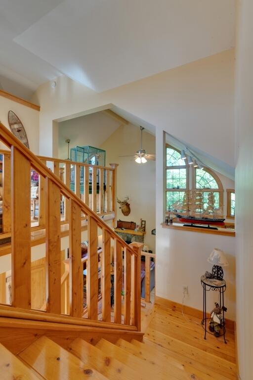 stairway featuring vaulted ceiling, ceiling fan, and hardwood / wood-style flooring