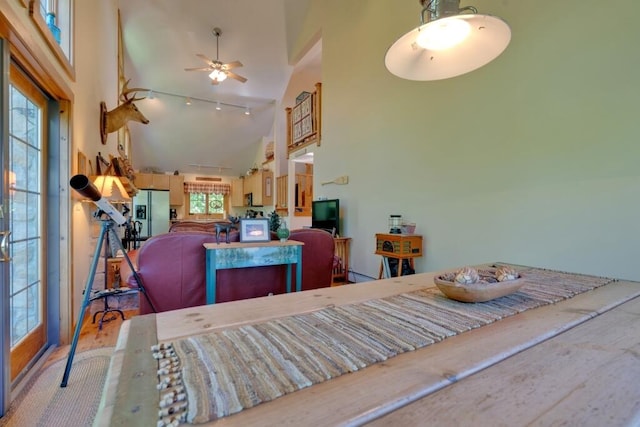 dining room with ceiling fan, light wood-type flooring, and high vaulted ceiling