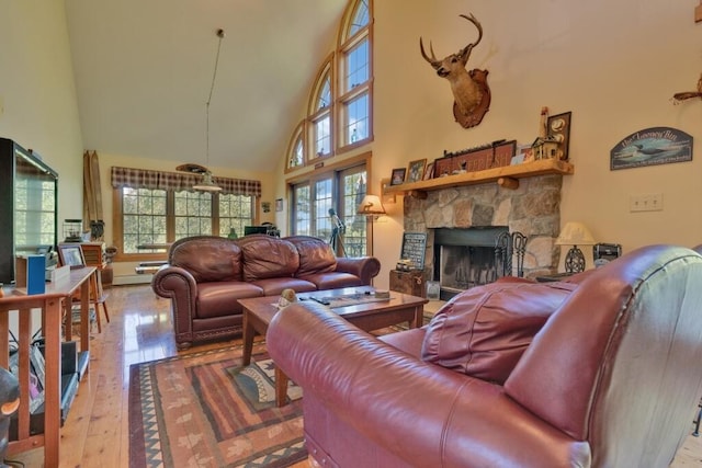 living room with a stone fireplace, hardwood / wood-style flooring, a towering ceiling, and a wealth of natural light