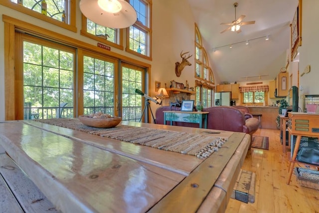 dining room with a wealth of natural light, ceiling fan, light hardwood / wood-style flooring, and high vaulted ceiling