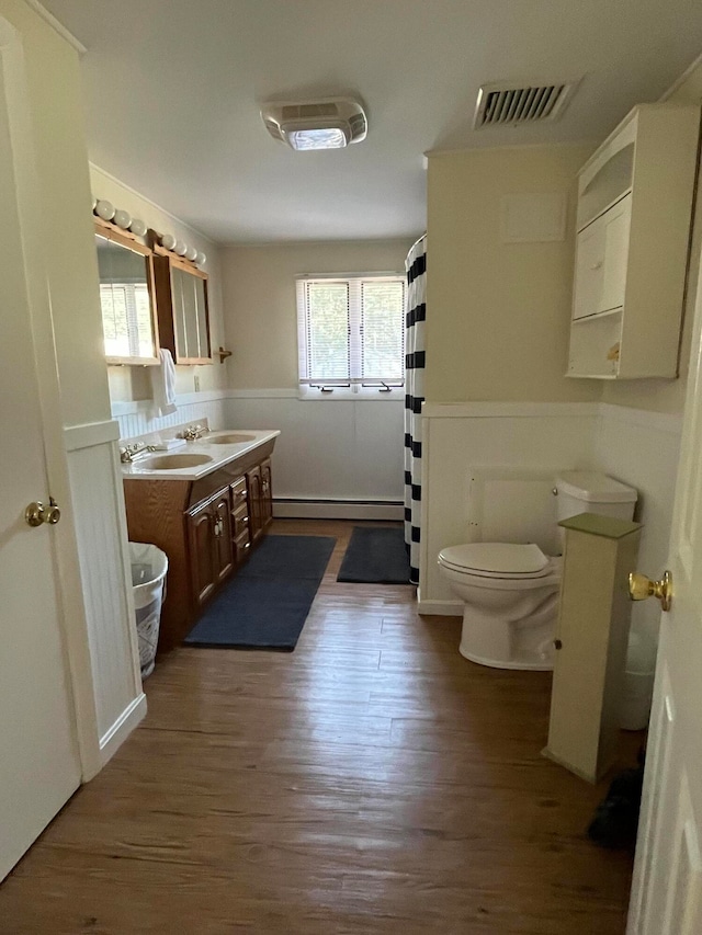 bathroom with wood-type flooring, vanity, a baseboard radiator, and toilet