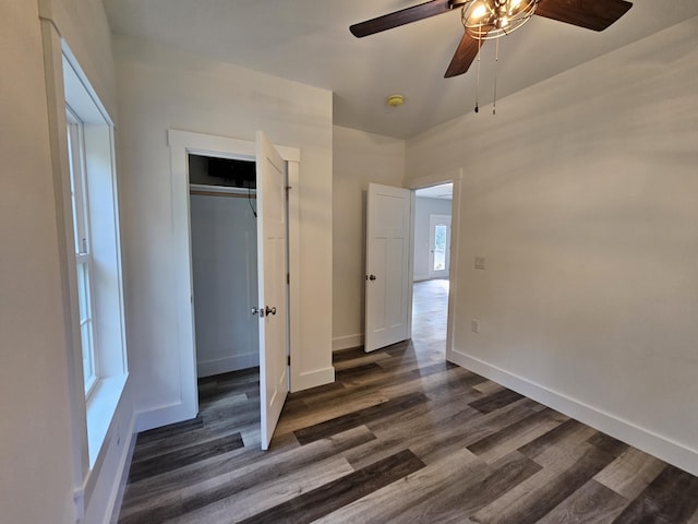 unfurnished bedroom featuring dark wood-style flooring, baseboards, a closet, and a ceiling fan