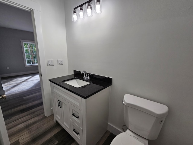 bathroom with toilet, hardwood / wood-style floors, and vanity