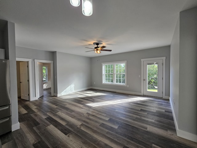 unfurnished living room with a ceiling fan, baseboards, and dark wood-style flooring