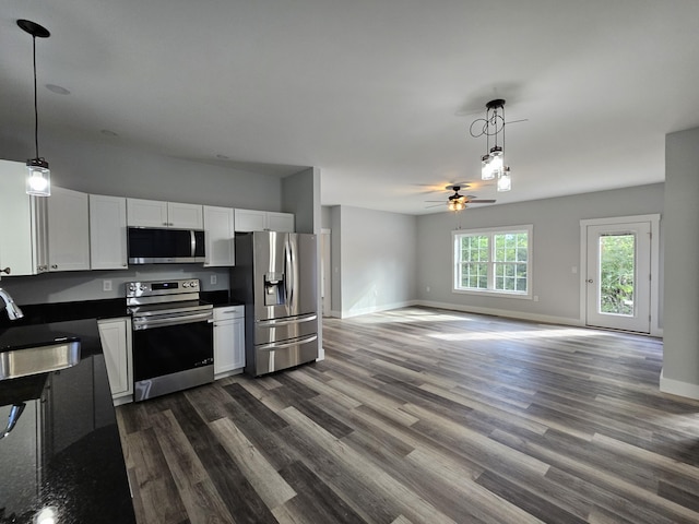 kitchen featuring appliances with stainless steel finishes, a ceiling fan, dark countertops, and dark wood finished floors