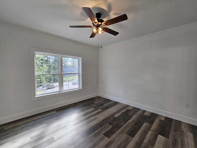 spare room with dark wood finished floors, a ceiling fan, and baseboards