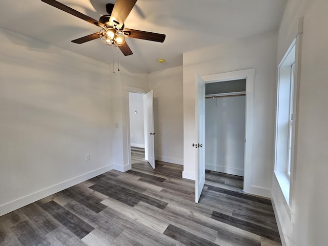 unfurnished bedroom with dark wood finished floors, baseboards, a closet, and ceiling fan