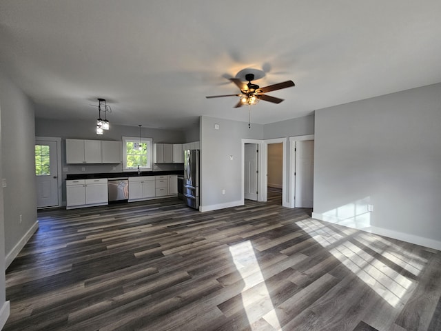 unfurnished living room with baseboards, a ceiling fan, and dark wood-type flooring