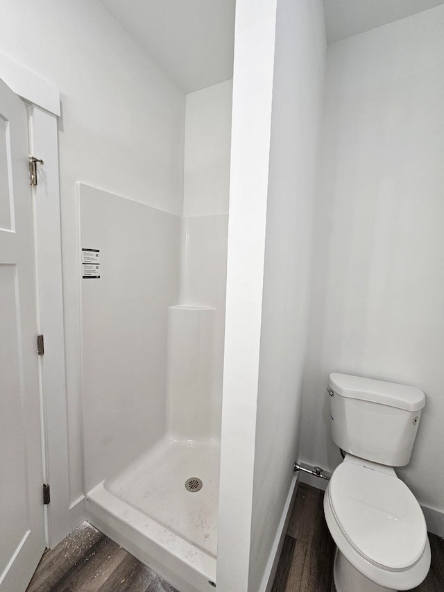 bathroom featuring hardwood / wood-style floors, toilet, and walk in shower