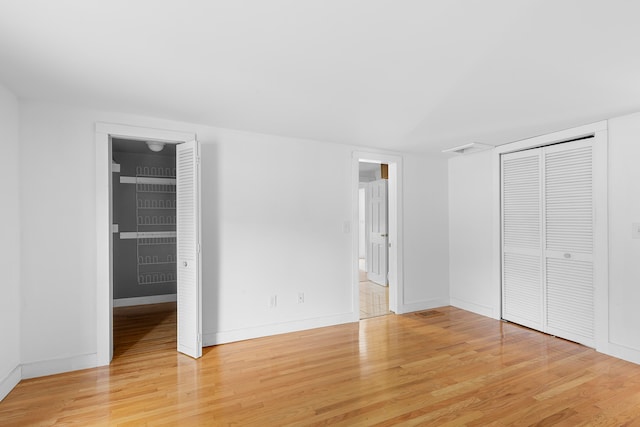 unfurnished bedroom featuring hardwood / wood-style floors and connected bathroom