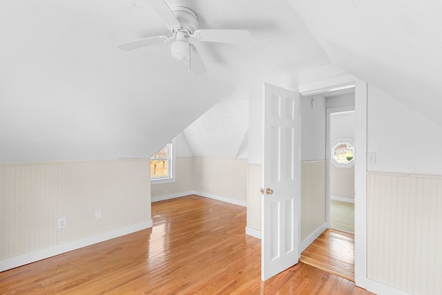 additional living space with light hardwood / wood-style floors, ceiling fan, a textured ceiling, and lofted ceiling