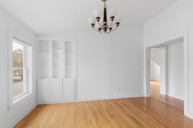 empty room with hardwood / wood-style flooring and an inviting chandelier