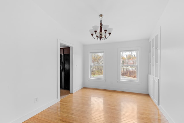 unfurnished dining area featuring a chandelier and light hardwood / wood-style floors