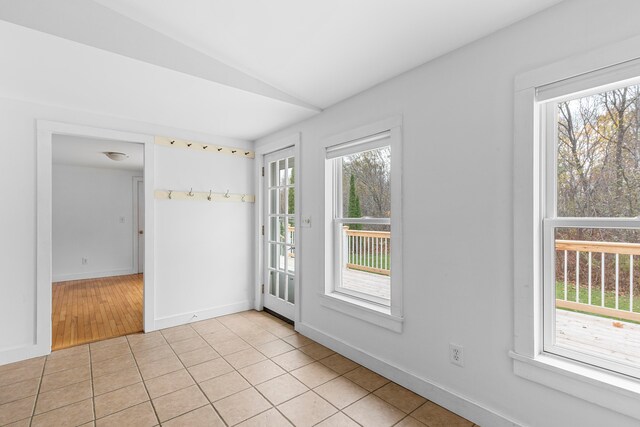 tiled empty room featuring vaulted ceiling